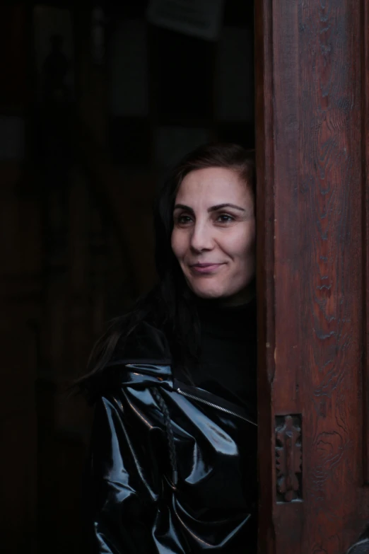 a woman standing in front of a wooden door, an album cover, inspired by Anna Füssli, pexels contest winner, renaissance, wearing leather coat, meni chatzipanagiotou, portrait close - up, foil