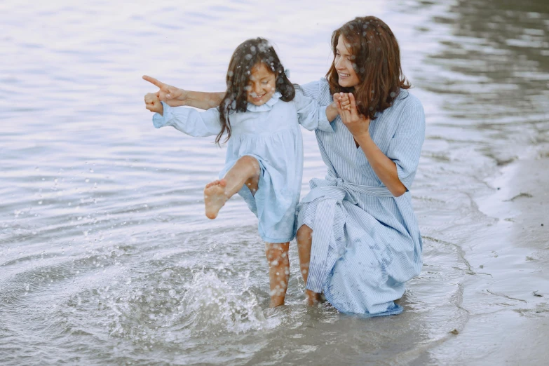 a mother and daughter playing in the water at the beach, pexels contest winner, symbolism, wearing blue robe, thumbnail, subtle details, animation