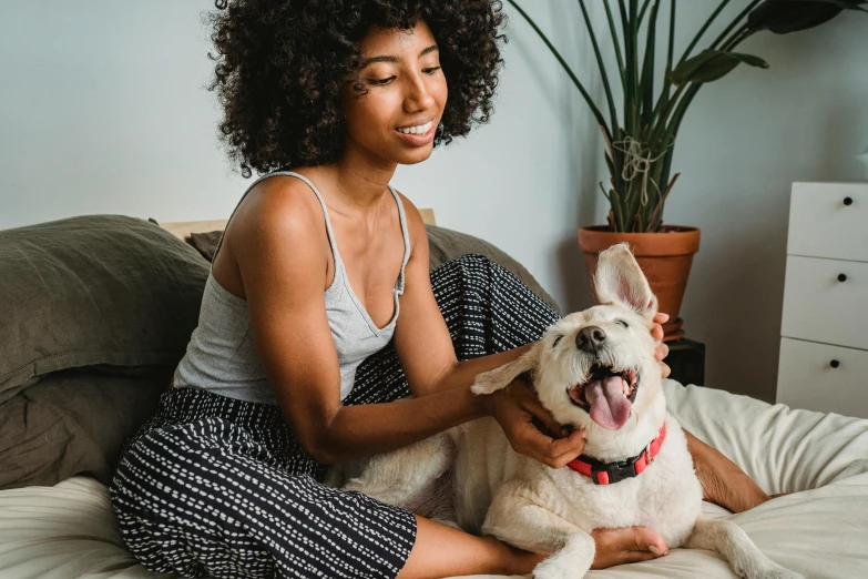 a woman sitting on a bed with a dog, pexels contest winner, happening, mixed-race woman, being delighted and cheerful, 1 4 9 3, aussie