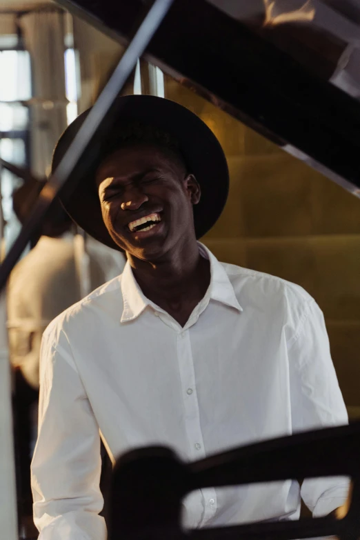 a man smiles as he plays a grand piano, by Ottó Baditz, trending on unsplash, adut akech, white suit and hat, wearing a white button up shirt, australian