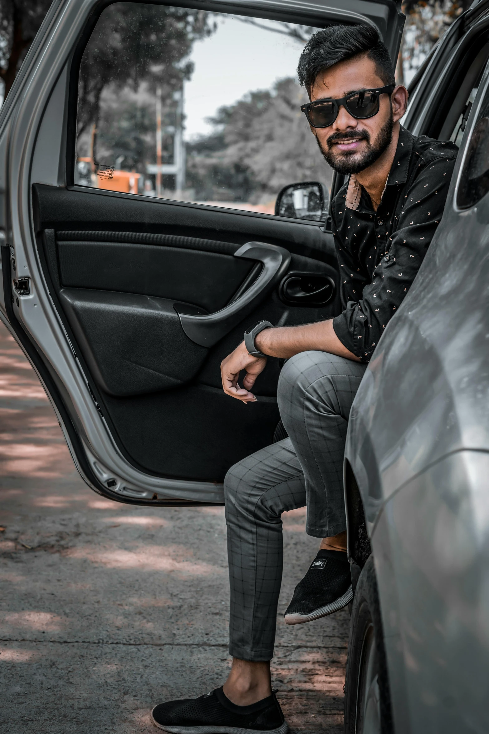 a man sitting in the open door of a car, pexels contest winner, indian super model, grey pants and black dress shoes, avatar image, coloured photo