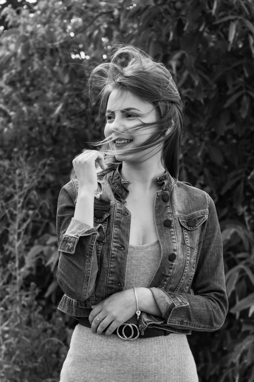 a black and white photo of a woman with her hair blowing in the wind, a black and white photo, inspired by Larry Fink, photorealism, emma!! watson!!, wearing a jeans jackets, sweet smile, 15081959 21121991 01012000 4k