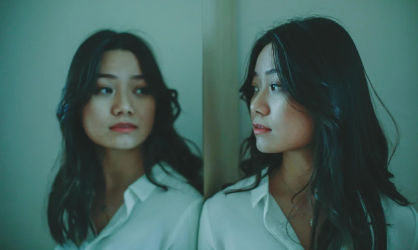 two women standing next to each other in front of a mirror, an album cover, inspired by Jung Park, pexels contest winner, gongbi, sad expression, wearing a white button up shirt, cinematic image