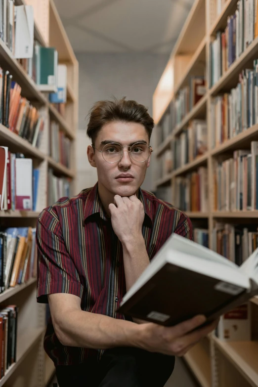 a man reading a book in a library, a portrait, pexels contest winner, non binary model, staring into the camera, russian academic, gif