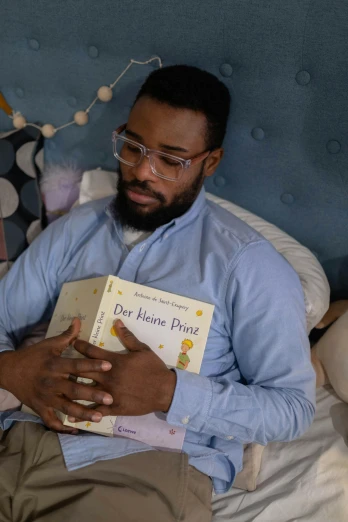 a man sitting on a bed reading a book, the little prince, jemal shabazz, lgbtq, slide show