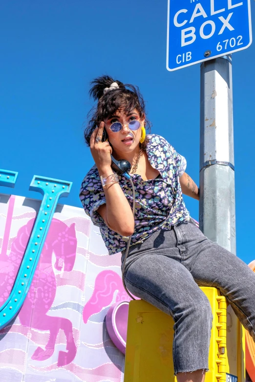 a woman sitting on top of a yellow box talking on a cell phone, trending on pexels, graffiti, charli xcx, in a las vegas street, ashteroth, blue sky