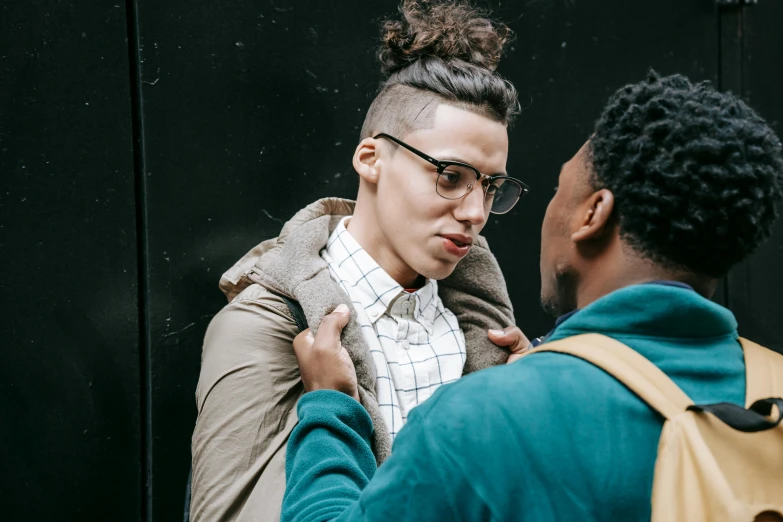 a man and a woman standing next to each other, by Nina Hamnett, trending on pexels, antipodeans, non binary model, man with glasses, two men hugging, about to enter doorframe