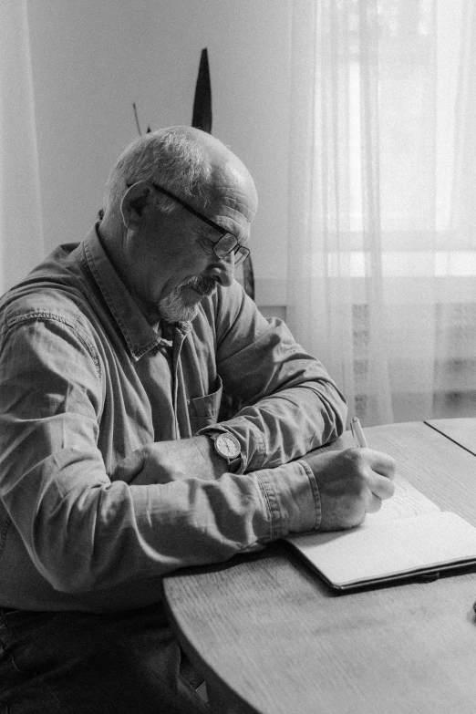 a man sitting at a table writing on a piece of paper, a black and white photo, by Jan Konůpek, portrait of hide the pain harold, mike ehrmantraut, profile image, uploaded