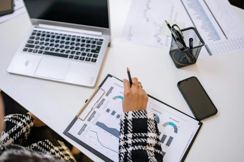 a woman sitting at a desk writing on a piece of paper, a picture, trending on pexels, analytical art, power bi dashboard, holding a clipboard, pictured from the shoulders up, excel running on the computer