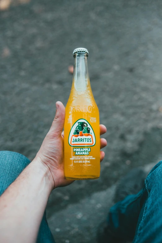 a person holding a bottle of orange juice, by James Jarvaise, pexels contest winner, mexican, largest haunches ever, 🐿🍸🍋, detailed product image