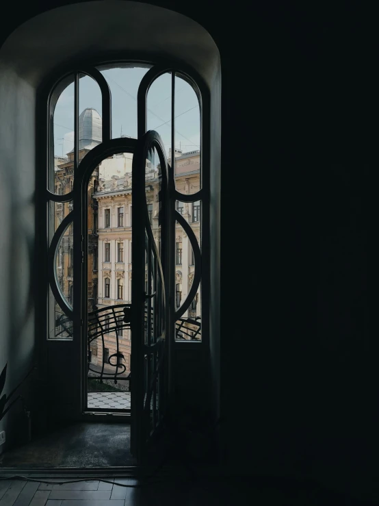 a view of a building through a window, inspired by André Kertész, unsplash contest winner, art nouveau, low quality photo, wrought iron, art nouveau ( 1 9 2 2 ), tall entry