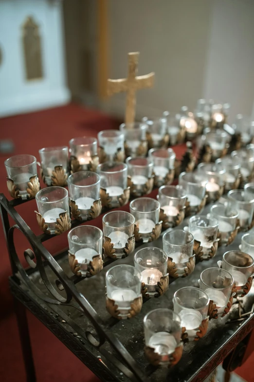 a bunch of glasses sitting on top of a table, on the altar, multiple lights, on a candle holder, image