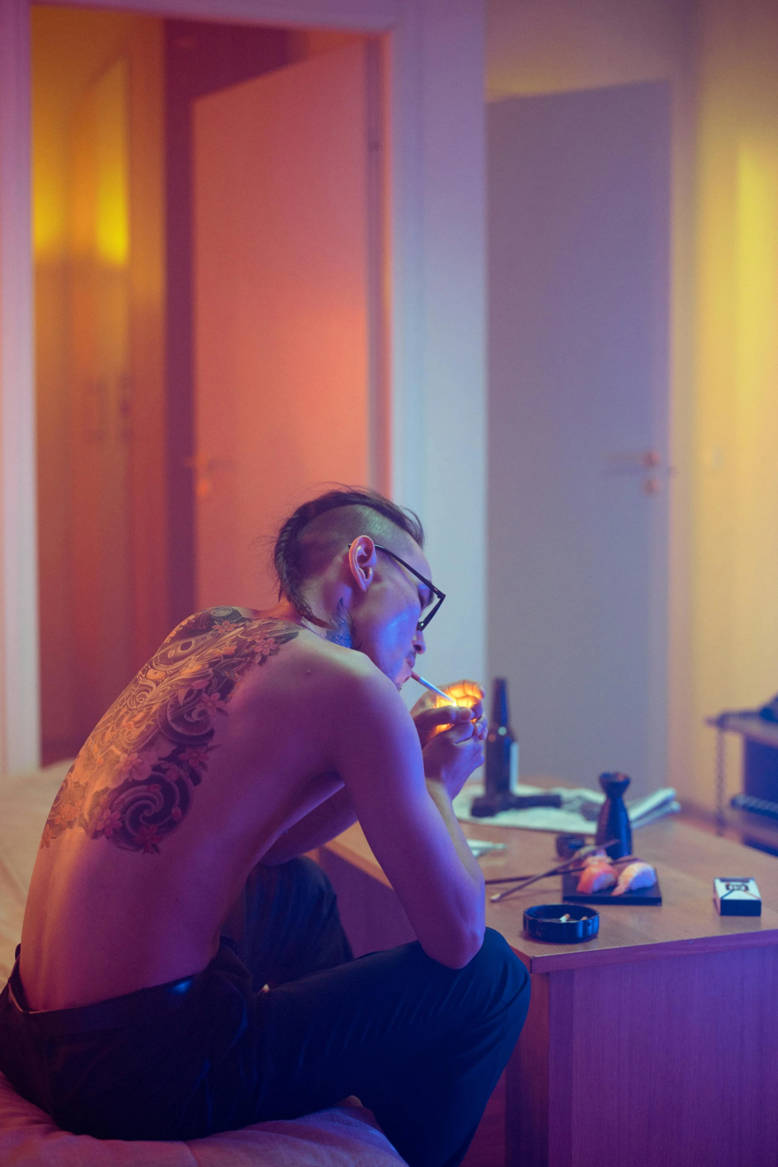 a man sitting on a bed in front of a tv, inspired by Nan Goldin, trending on pexels, detailed neon tattoos, drinking at the bar, smoking a bowl of hash together, profile image