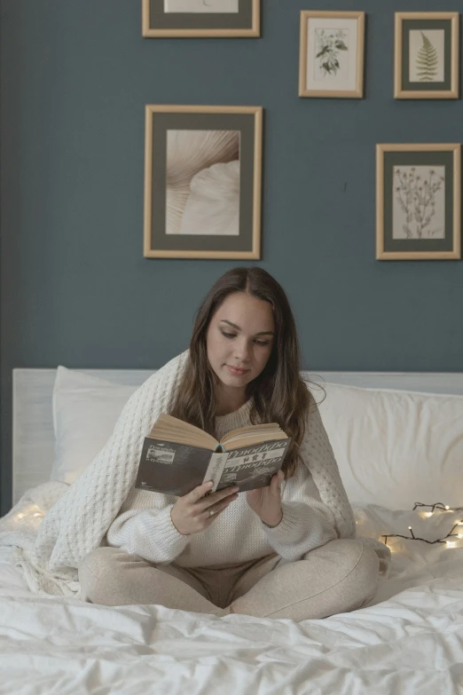 a woman sitting on a bed reading a book, inspired by Louisa Matthíasdóttir, happening, clean soft lighting, promo image, small and cosy student bedroom, winter time