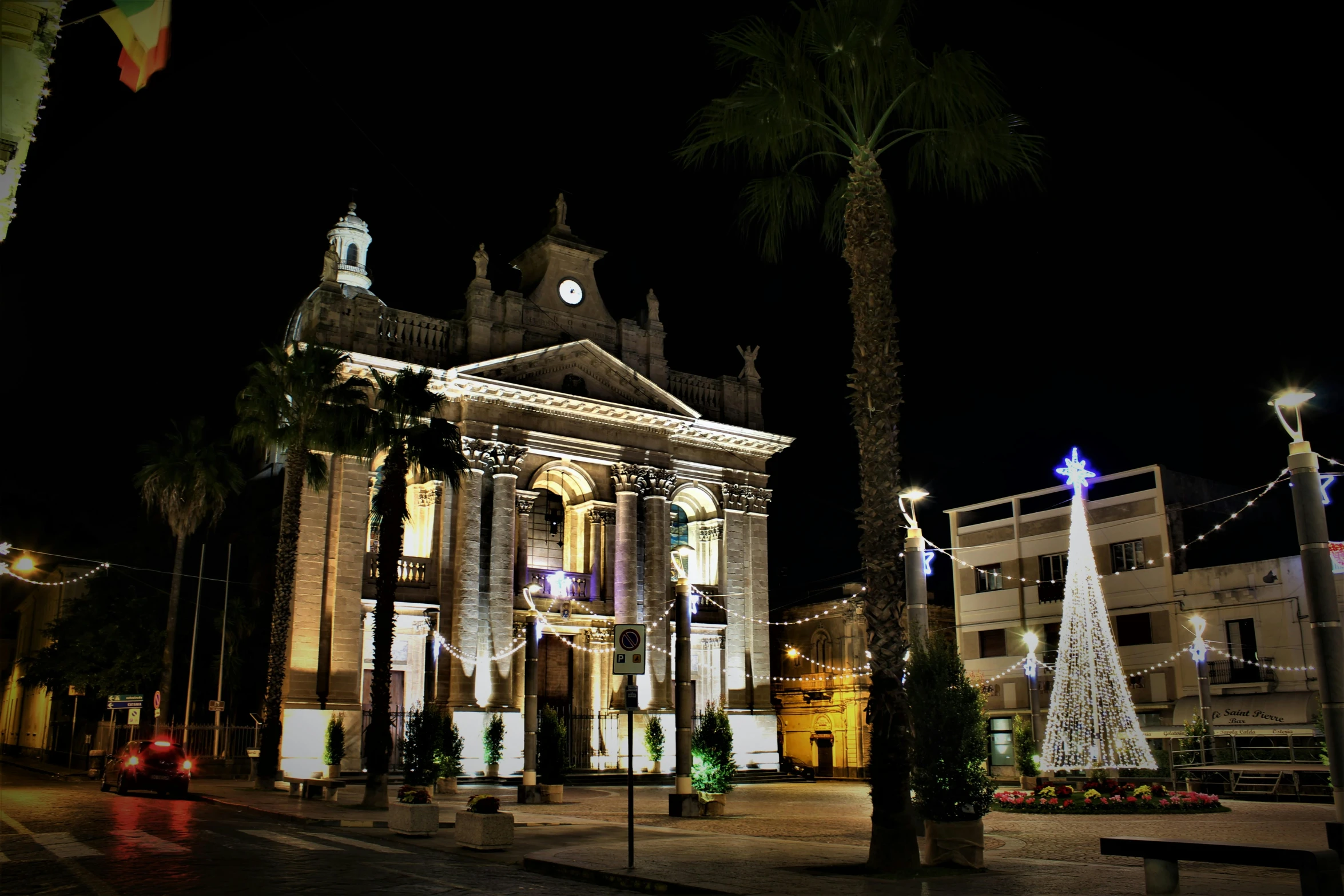 a large building with a christmas tree in front of it, costa blanca, cathedral, light and dark, with palm trees and columns