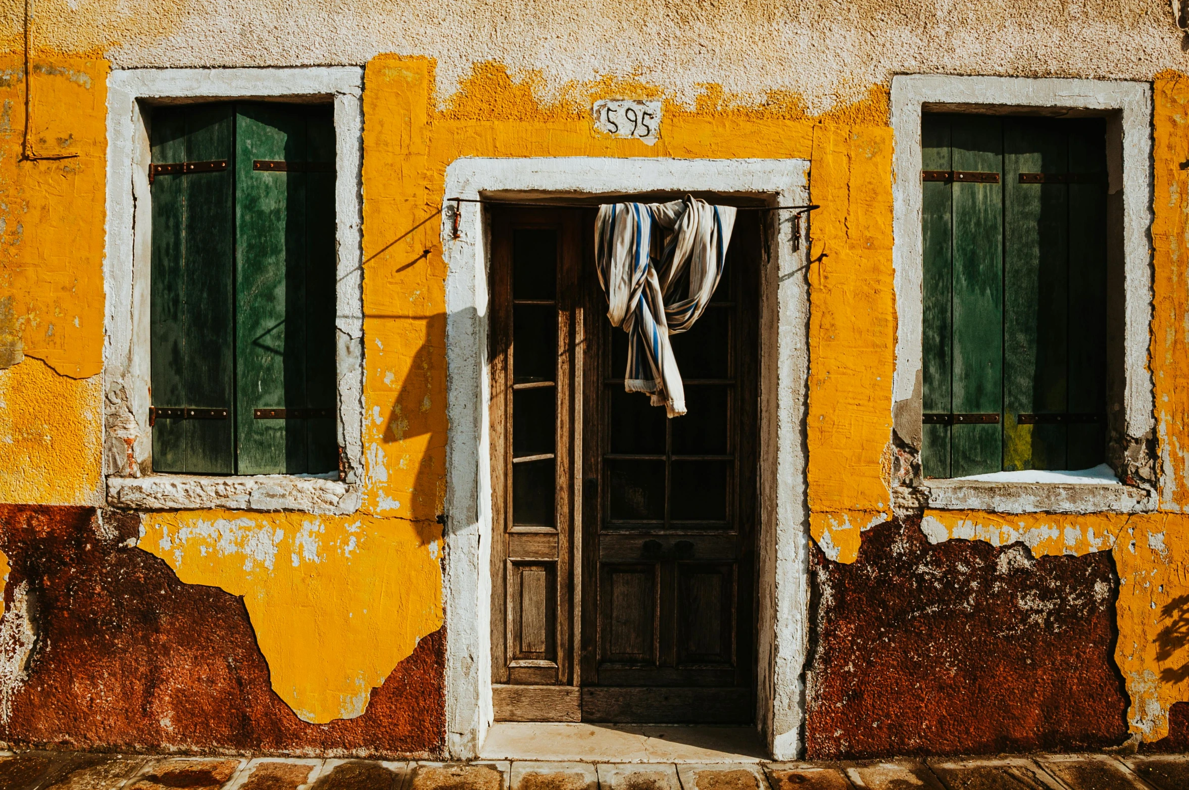 a red fire hydrant sitting in front of a yellow building, inspired by Marià Fortuny, pexels contest winner, arte povera, laundry hanging, doorway, green and brown clothes, standing outside a house