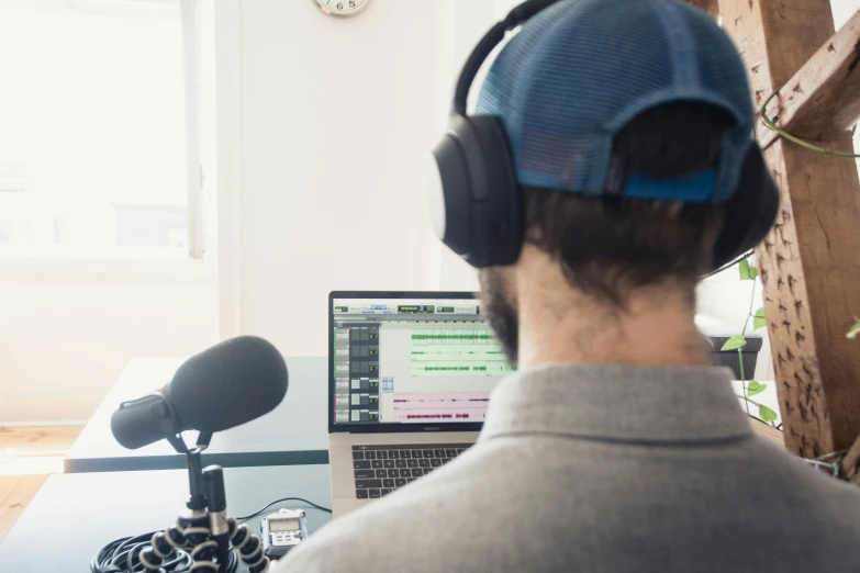 a man sitting in front of a laptop wearing headphones, by Niko Henrichon, studio microphone, from the distance, avatar image, high quality upload