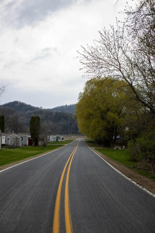 a street with a yellow line in the middle of it, a picture, inspired by Gregory Crewdson, rolling foothills, 8 k wide shot, early spring, touring