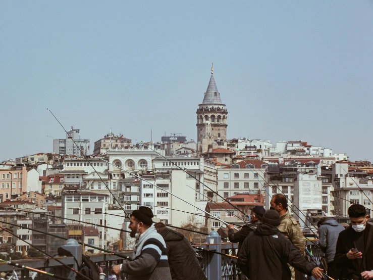 a group of people standing on top of a bridge, by Tamas Galambos, pexels contest winner, hurufiyya, expansive detailed layered city, turkish and russian, on a bright day, grayish