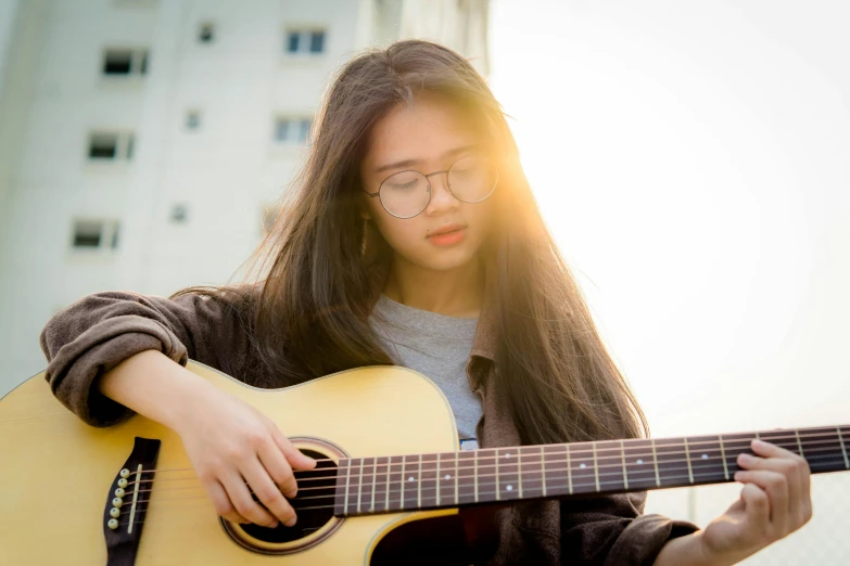 a woman with glasses playing an acoustic guitar, trending on pexels, realism, asian girl with long hair, full morning sun, rectangle, instagram post