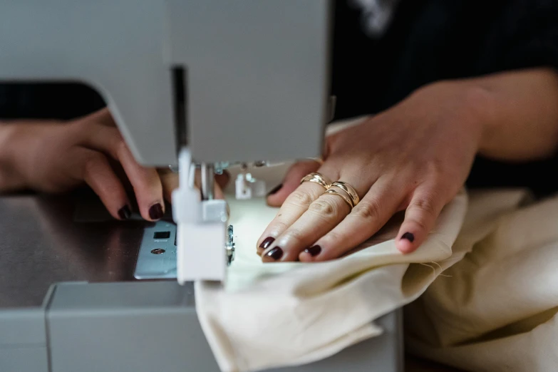 a close up of a person using a sewing machine, wearing silver silk robe, eight eight eight, sleek hands, restoration