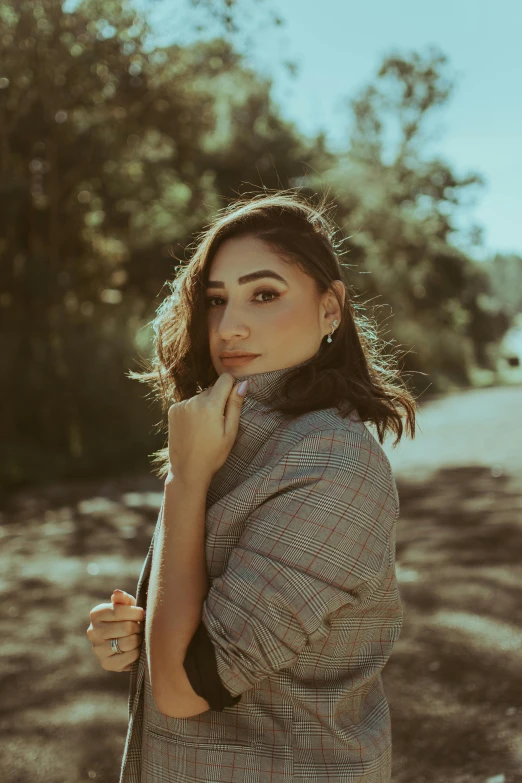 a woman standing in the middle of a dirt road, flawless olive skin, wearing a fancy jacket, flannel, promo image