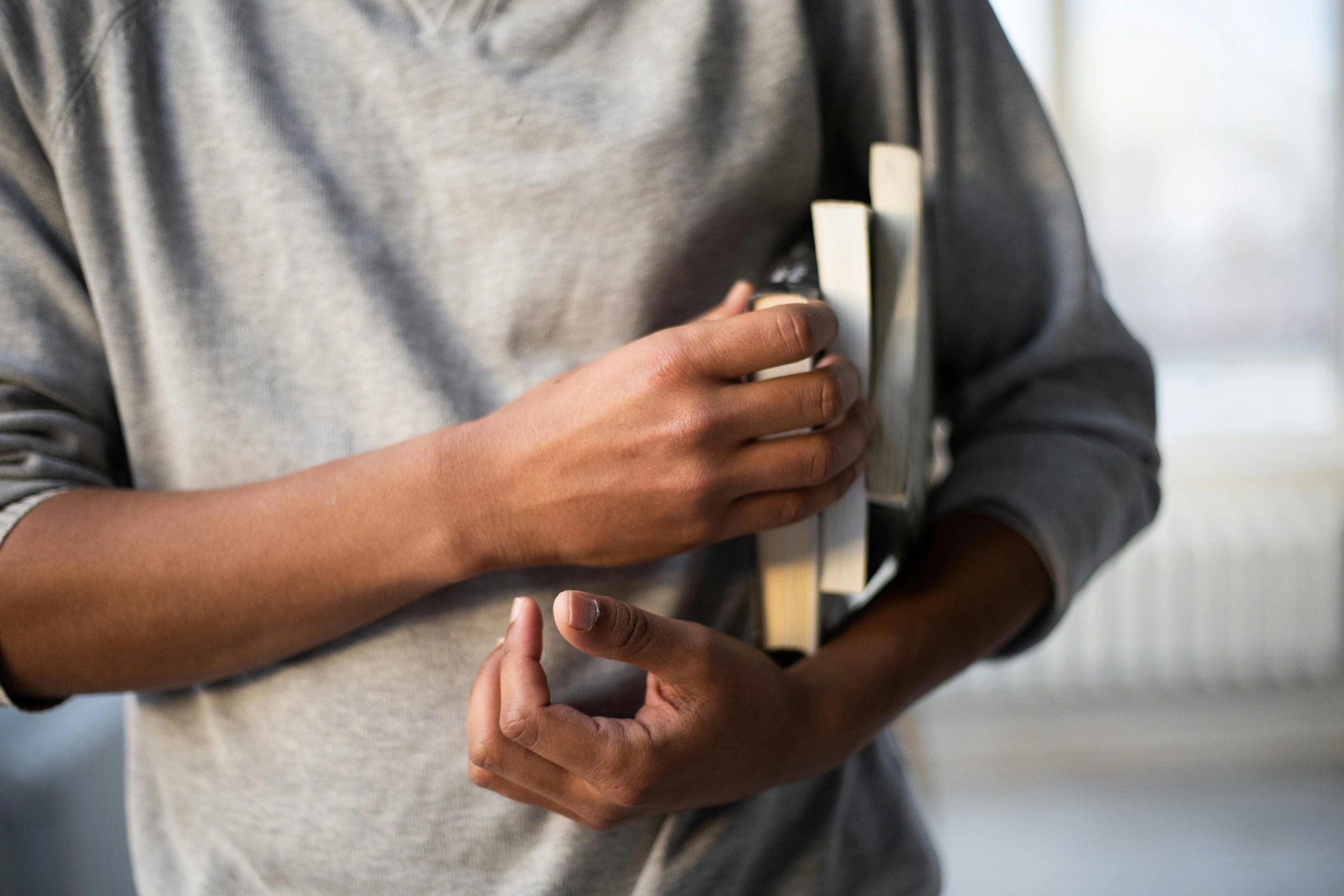 a close up of a person holding a book, by Sven Erixson, pexels contest winner, private press, metal handles, grey metal body, plated arm, holding a very advance phone