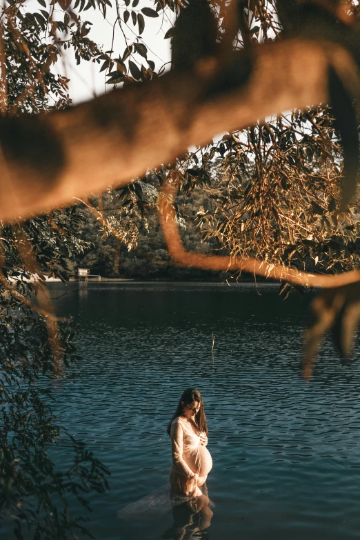 a person standing in a body of water, sitting under a tree, manly, gemma chen, in lake