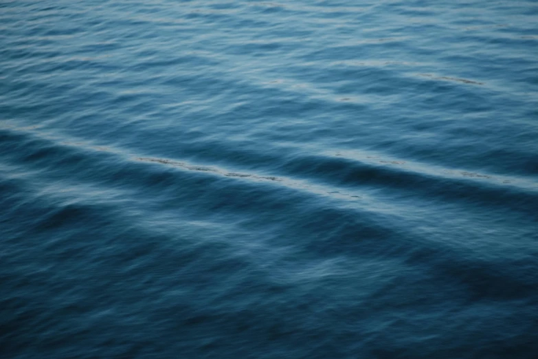 a large body of water with a boat in the distance, a picture, by Elsa Bleda, hurufiyya, the blue whale crystal texture, unsplash 4k, ripples, ignant