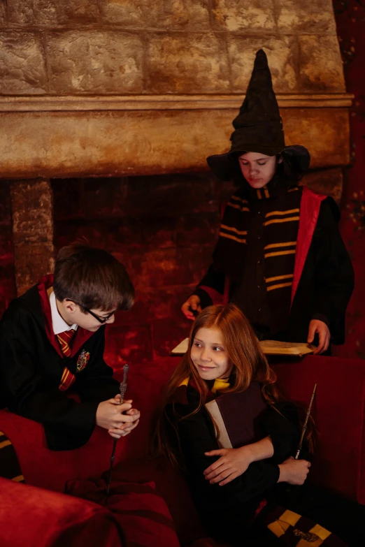 a group of people sitting on top of a red couch, wizard robe, marauders map, kids playing, in london