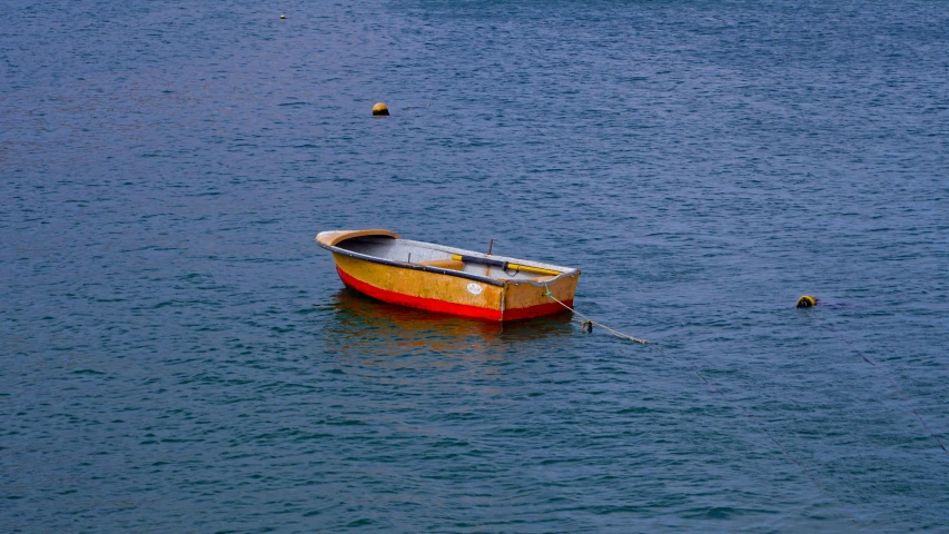 a small boat floating on top of a body of water, pexels contest winner, red and teal and yellow, breton cap, completely empty, wellington