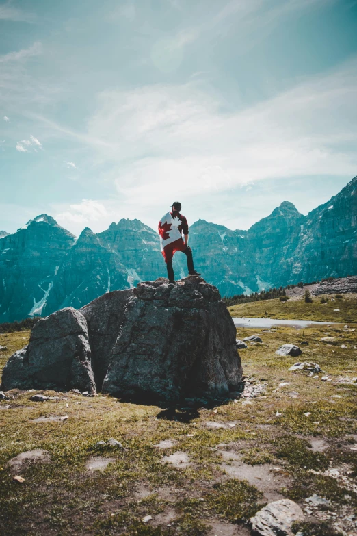 a person standing on top of a large rock, banff national park, on top of a hill, on the top of a hill