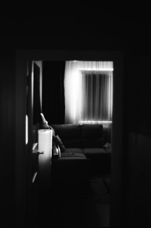 a person sitting on a couch in a dark room, a black and white photo, unsplash contest winner, light and space, pinhole analogue photo quality, in my bedroom, about to enter doorframe, :: morning