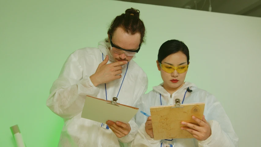 a couple of people standing next to each other, analytical art, writing on a clipboard, goggles on forehead, production photo, taejune kim