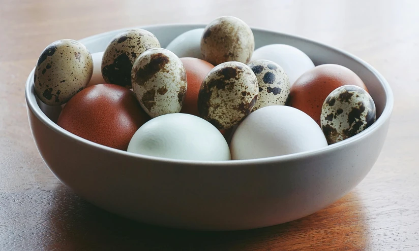 a bowl filled with eggs on top of a wooden table, unsplash, 🦩🪐🐞👩🏻🦳, various colors, white with chocolate brown spots, hasbulla