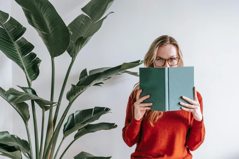 a woman reading a book in front of a plant, pexels contest winner, nerdy appearance, wearing green clothing, avatar image, studio photo