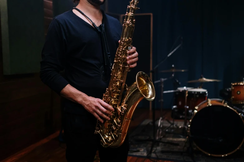 a man holding a saxophone in a room, shaft studio, medium level shot, brass equipment and computers, trending arstationhq