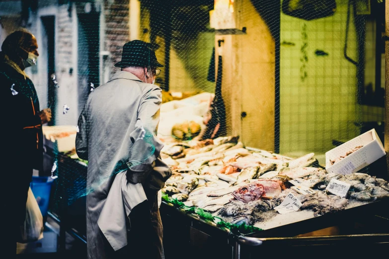 a man standing in front of a display of fish, by Julia Pishtar, pexels contest winner, renaissance, fresh food market people, profile image, stood outside a corner shop, closeup of a butcher working