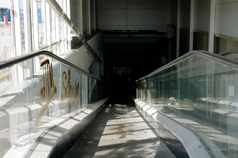 a couple of escalators sitting next to each other, inspired by Thomas Struth, unsplash, graffiti, everything seems abandoned, white gallery, glass floor, a long-shot from front