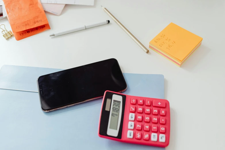 a cell phone sitting on top of a desk next to a calculator, a picture, pink and red color scheme, thumbnail, educational supplies, no - text no - logo