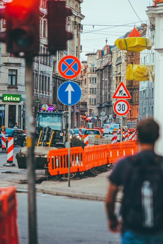 a man walking down a street next to a traffic light, by Tobias Stimmer, pexels contest winner, happening, construction site, lots of signs, 🚿🗝📝, banner