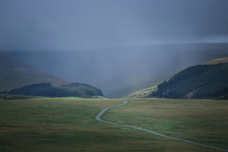 a road in the middle of a field with mountains in the background, by Muggur, unsplash contest winner, les nabis, heavy rain from thick clouds, forest plains of north yorkshire, overview, shot on hasselblad