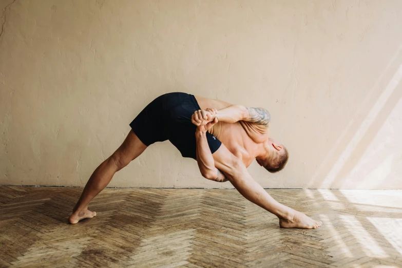 a man doing a yoga pose on a hard wood floor, by Matija Jama, pexels contest winner, heroic shooting bow pose, triangle, profile image, thumbnail