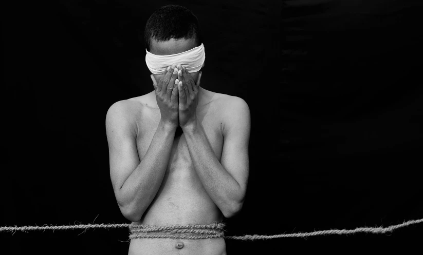 a black and white photo of a man tied to a rope, an album cover, inspired by Roger Ballen, pexels contest winner, renaissance, 14 yo berber boy, with black eyes, islamic, disrobed