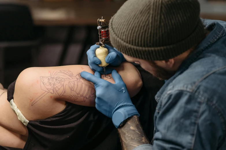 a man getting a tattoo on a woman's thigh, a tattoo, by Adam Marczyński, trending on pexels, blue ink, down left arm and back, enlightening, holding an epée