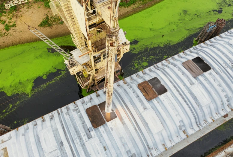 a crane that is next to a body of water, by Carey Morris, pexels contest winner, conceptual art, high angle vertical, silo, green gas spreading across land, cardboard