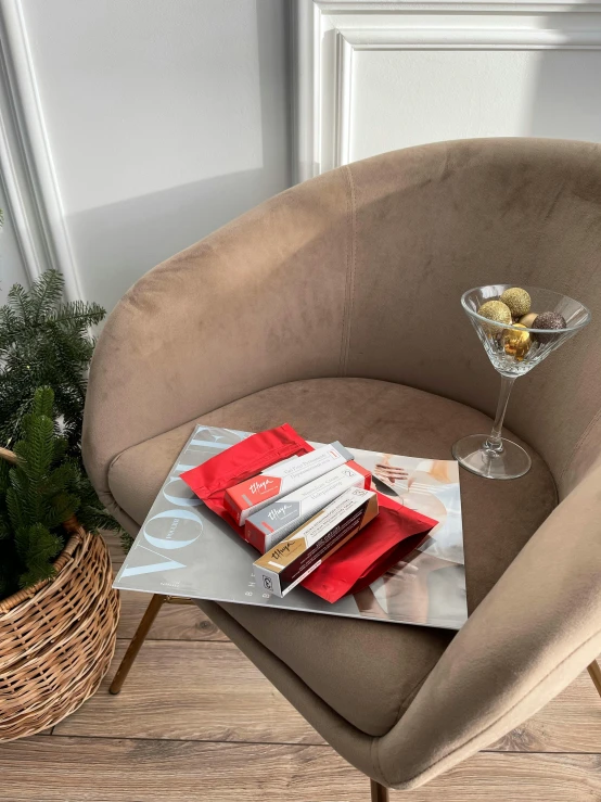 a chair sitting on top of a wooden floor next to a table, an album cover, dressed in red paper bags, champagne, product display photograph, reading a newspaper