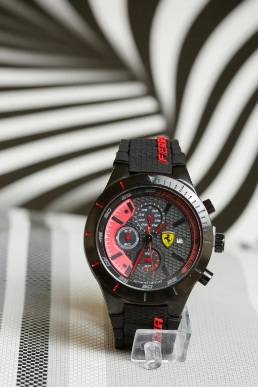 a close up of a watch on a table, inspired by Francesco Furini, pexels, pop art, ferrari logo on it's chest, black and red only, thumbnail, square