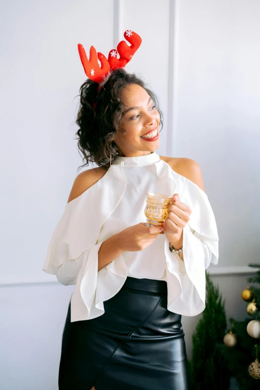 a woman standing in front of a christmas tree, by Dulah Marie Evans, holding a drink, cream colored blouse, curls on top, wearing a paper crown