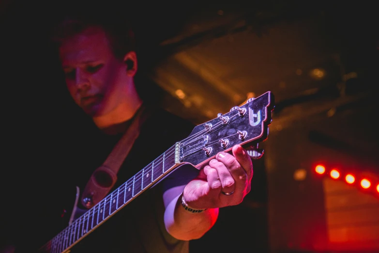 a close up of a person playing a guitar, private press, club photography, the tesseract, looking off to the side, dan munford